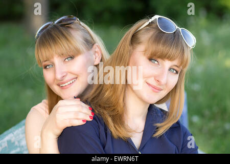 Zwei hübsche Frauen, die Spaß an der Sommerpark. Zwillinge-Mädchen posieren auf der Kamera Stockfoto