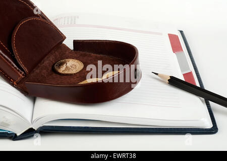 Geldbörse mit einem Dollar Münze auf das Tagebuch und Stift Stockfoto