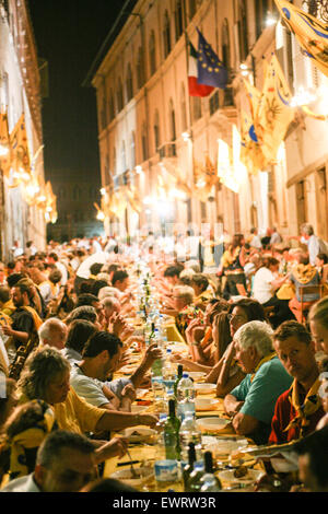 Essen Abendessen in einer Nachbarschaft zu sammeln. Siena ist in 17 Contrade Nachbarschaft Bezirke unterteilt und die Nachbarschaften haben ein großes Abendessen am Vorabend der wichtigsten Palio-Pferderennen. In der zentralen Siena, Toskana. Italien. Juli. Stockfoto