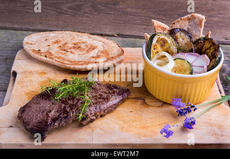 Provenzalischen Stil Pferd Fleisch Entrecote Steak mit Ratatouille und Fladenbrot serviert auf einem Holzbrett, dekoriert mit Lavendel und Stockfoto