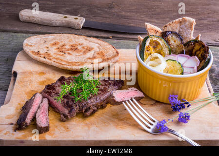 Provenzalischen Stil Pferd Fleisch Entrecote Steak mit Ratatouille und Fladenbrot serviert auf einem Holzbrett, dekoriert mit Lavendel und Stockfoto