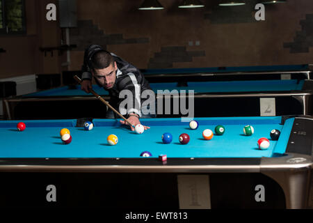 Junger Mann Futter um Ball auf Billardtisch Stockfoto