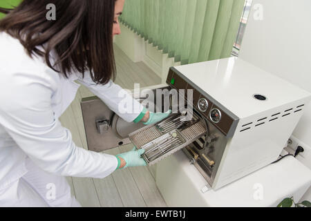 Junge Zahnärztin Orte medizinische Autoklav für die Sterilisation chirurgischer und andere Instrumente Stockfoto