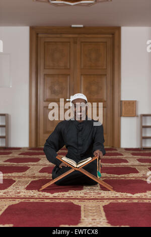 Schwarze afrikanische muslimischen Mann Lesung islamische heilige Buch Koran Stockfoto