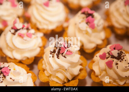 Herb lässt Mini Kuchen mit gesichert Schlagsahne weißen weichen mit bunten rosa Dekorationen und Schokolade Chips in kleinen Körben Stockfoto