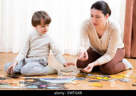 Kind eine Etage zu lösen Rätsel zu Hause von seiner Mutter geholfen Stockfoto