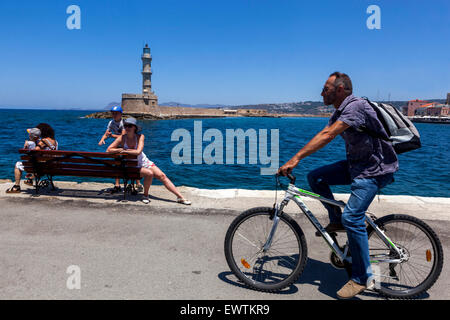 Mann auf der Uferpromenade Fahrt ein Fahrrad vor dem alten Leuchtturm in der Venezianischen Hafen Chania Kreta Griechenland Stockfoto