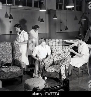 1950er Jahre, historische Frauen in weißen Overalls, die an einem Abendkurs teilnehmen, einem Polsterkurs, wo sie gemusterte lose Bezüge für Sessel herstellen und anbringen, England, Großbritannien. Stockfoto