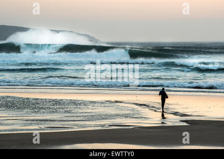 Bodysurfer stehen am Strand bei Sonnenuntergang in Cornwall nach großen Wellen zum Surfen. Stockfoto