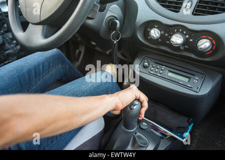 Frau Auto zu fahren, Nahaufnahme von einer Hand auf manuellen Schalthebel. Innenraum des Wagens unscharf gestellt und selektiven Fokus auf der Seite. Stockfoto