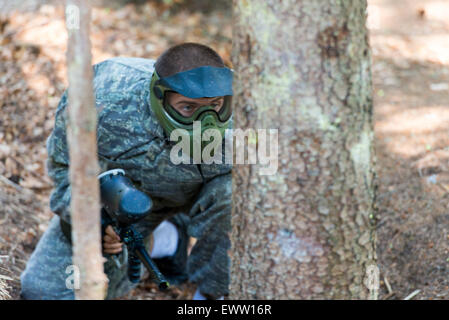 Paintball-Spieler verstecken sich hinter Baum Stockfoto