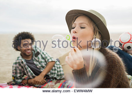 Frau bläst Seifenblasen auf Strand