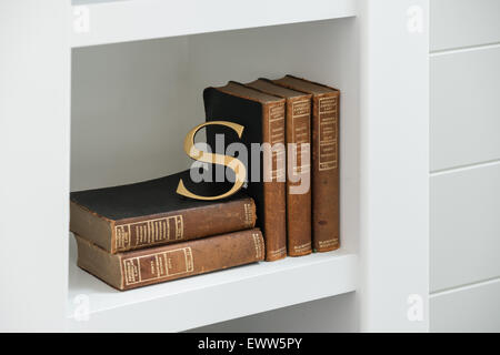 Gold Buchstaben S lehnte sich auf antike Bücher in modernen Vitrinen Stockfoto