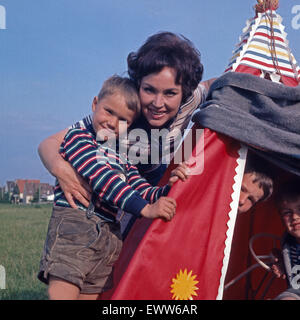 Die deutsche Sängerin und Plant Monika Dahlberg spielt mit den Kindern Indianer, Deutschland 1960er Jahre. Deutsche Sängerin und Schauspielerin Monika Dahlberg spielen mit den Kindern, Deutschland der 1960er Jahre. 6x6-Dia 15. Stockfoto