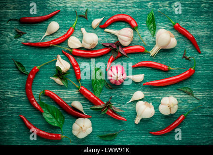 Rote Chilischoten, Knoblauch und Basilikum über einem hölzernen Hintergrund Stockfoto