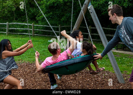 Eine Familie spielen auf Schaukeln, Play Area, Sussex, Großbritannien Stockfoto