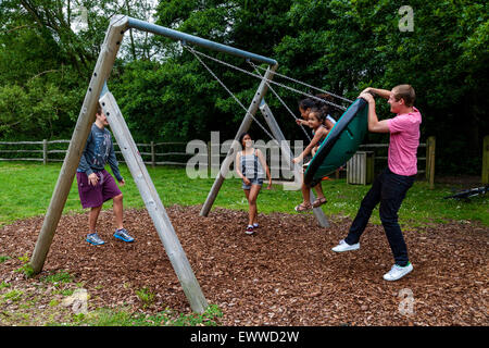 Eine Familie spielen auf Schaukeln, Play Area, Sussex, Großbritannien Stockfoto