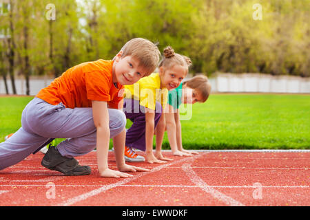 Zwei Jungs und Mädchen stehen auf Knie startbereit Stockfoto