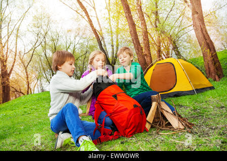 Drei Kinder, die Dinge in roten Rucksack packen Stockfoto