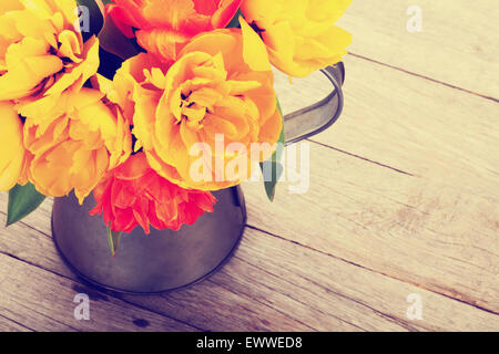 Bunte Tulpen Strauß in Gießkanne auf Holztisch. Draufsicht mit Textfreiraum. Retro, getönt Stockfoto
