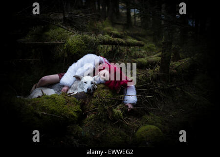 Der Stoff aus dem Träume und Alpträume: ein Junge rote kurzhaarige kaukasischen Frau Mädchen allein in einem dunklen Kiefernwald mit einem weißen Wolf-ähnlichen Hund schlafen Stockfoto