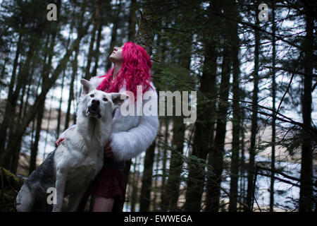 Der Stoff aus dem Träume und Alpträume: ein Junge rote kurzhaarige kaukasischen Frau Mädchen allein in einem dunklen Kiefernwald mit einem weißen Wolf-ähnlichen Hund Stockfoto