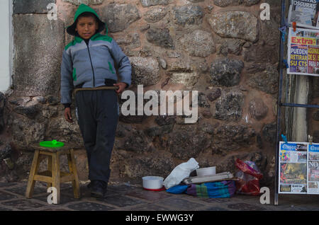 Junge, stehen gegen eine Steinmauer in Cusco, Peru, Verkauf von Gegenständen. Stockfoto