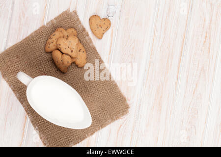 Herzform Lebkuchen und Milch Krug. Auf weißer Holztisch Stockfoto