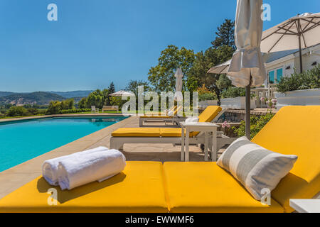 Moderne, helle gelbe Liegestühle am Pool Stockfoto