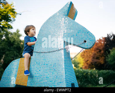 Kleiner Junge reitet Spielzeug Pferd keramischen Fliese Stockfoto