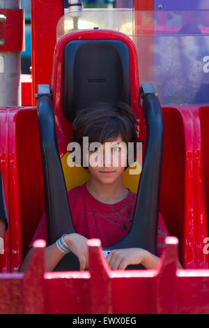 Junge mit einem besorgt Sitz einer Fahrt in einem Vergnügungspark. Stockfoto