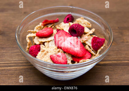 Schüssel mit Müsli und Obst auf Holztisch Stockfoto