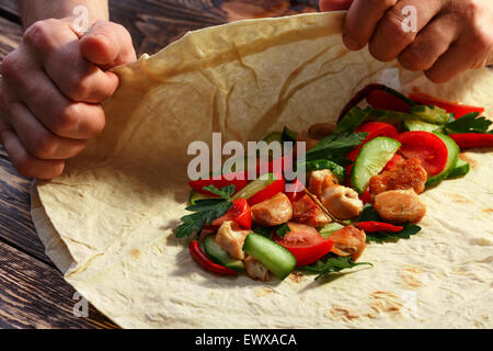 Männerhände Verpackung traditionelle Shawarma wickeln mit Huhn und Gemüse Stockfoto