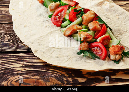 Traditionelle Shawarma Wrap mit Hähnchen und Gemüse auf Holztisch kurz vor Umhüllung. Große Schärfentiefe-Feld, detailliertes Bild Stockfoto