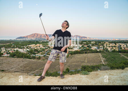 Kerl mit Selfie Stick versuchen, cool aussehen Stockfoto