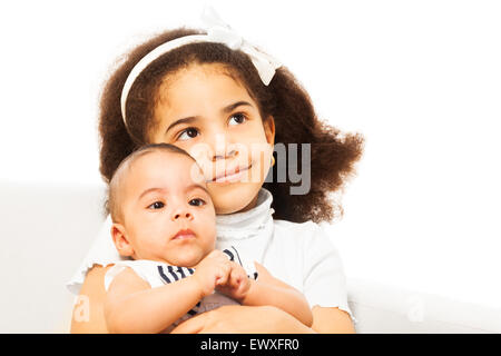 Schönes afrikanische Mädchen hält Schwester Baby in armen Stockfoto