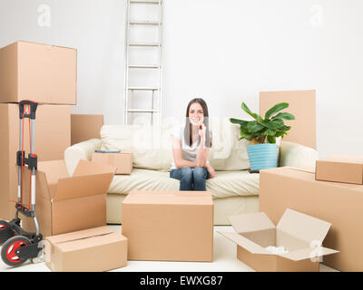 glückliche junge Frau sitzen auf Sofas umgeben von Pappe-Boxen in ihrem neuen Haus Stockfoto