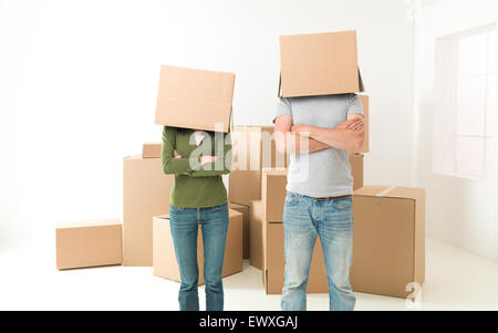 paar mit Kästen auf ihre Köpfe stehen in ihrem neuen Haus vor der Brust verschränkten Armen Stockfoto
