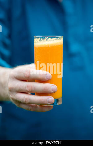 Mann, der eine frische Karotte und orange smoothie Stockfoto