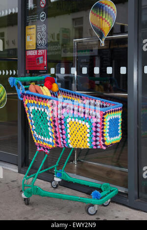 Garnbomben, Bomben, yarnbombing, farbenfrohe dekorative Strickwaren, Co-op Supermarkt-Einkaufswagen, Drahtwagen, Westhearthughton, Lancashire, Großbritannien Stockfoto