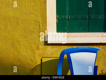 Blaue und weiße gebrochen Kunststoff-Stuhl vor einem grün lackierten Haus bei Sonnenaufgang Burano venezianischen Lagune Veneto Italien Europa Stockfoto