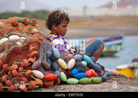 Kreolische junge ruht gegen Fischernetze im Hafen des Fischerdorfes Palmeira auf der Insel Sal, Kap Verde / Cab Verde Stockfoto