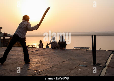 Lokalen Jungs über die Badegewässer Ghat, spielen beliebter Nationalsport Cricket bei Sonnenaufgang. Einen guten Hit und der Ball geht in die Fluss-G Stockfoto