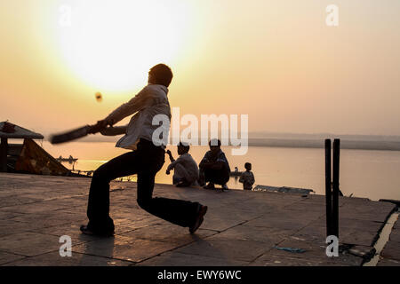 Lokalen Jungs über die Badegewässer Ghat, spielen beliebter Nationalsport Cricket bei Sonnenaufgang. Einen guten Hit und der Ball geht in den Fluss Ganges. Die Kultur von Varanasi ist eng mit dem Fluss Ganges und religiöse Bedeutung des Flusses. Es ist "die religiöse Hauptstadt des India'and ein wichtiges Wallfahrtsziel. Varanasi, auch bekannt als Benares, eine alte Stadt, eine der ältesten kontinuierlich bewohnten Städte der Welt, liegt am Ufer des heiligen Flusses Ganges links/West. Gelten als heilig durch Hindus, Buddhisten und Jains. Staat Uttar Pradesh, Indien, Asien. Stockfoto