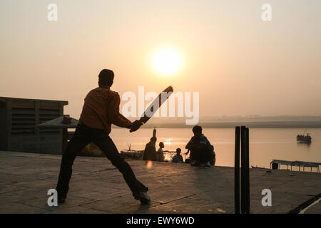 Lokalen Jungs über die Badegewässer Ghat, spielen beliebter Nationalsport Cricket bei Sonnenaufgang. Einen guten Hit und der Ball geht in die Fluss-G Stockfoto