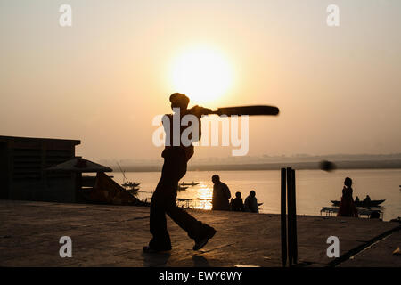 Lokalen Jungs über die Badegewässer Ghat, spielen beliebter Nationalsport Cricket bei Sonnenaufgang. Einen guten Hit und der Ball geht in den Fluss Ganges. Die Kultur von Varanasi ist eng mit dem Fluss Ganges und religiöse Bedeutung des Flusses. Es ist "die religiöse Hauptstadt des India'and ein wichtiges Wallfahrtsziel. Varanasi, auch bekannt als Benares, eine alte Stadt, eine der ältesten kontinuierlich bewohnten Städte der Welt, liegt am Ufer des heiligen Flusses Ganges links/West. Gelten als heilig durch Hindus, Buddhisten und Jains. Staat Uttar Pradesh, Indien, Asien. Stockfoto