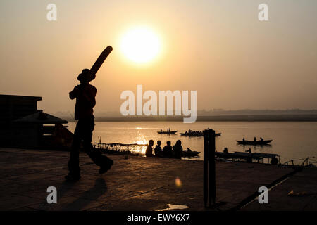 Lokalen Jungs über die Badegewässer Ghat, spielen beliebter Nationalsport Cricket bei Sonnenaufgang. Einen guten Hit und der Ball geht in die Fluss-G Stockfoto