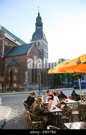 Dom zu Riga, die evangelischen Dom von Riga ist. Die größte mittelalterliche Kirche in den baltischen Staaten ist es oft in englischer Sprache als der Dom bekannt. Am Domplatz, hier mit Menschen sitzen auf dem Platz in einem Café/Bar Steakrestaurant 13 Kresli(13 Chairs) in der Altstadt, im Zentrum von Riga, die Hauptstadt von Lettland. Mai. Stockfoto