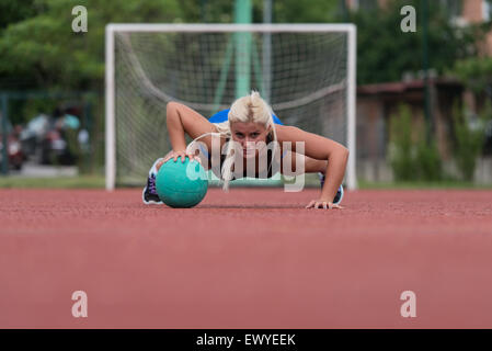 Junge Frau im Freien durchführen von Push-Ups auf Medizinball Bodybuilding Übung Stockfoto