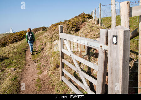 Weibliche Wanderer veröffentlichte Modell, mit Strumble Head Leuchtturm in der Ferne auf den Pembrokeshire Coast Path, Südwesten von Wales. M Stockfoto